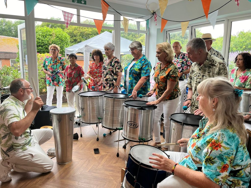 A side view of musicians playing on percussive instruments with a natural backdrop