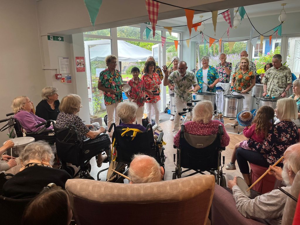 Musicians playing on percussive instruments before an elderly audience