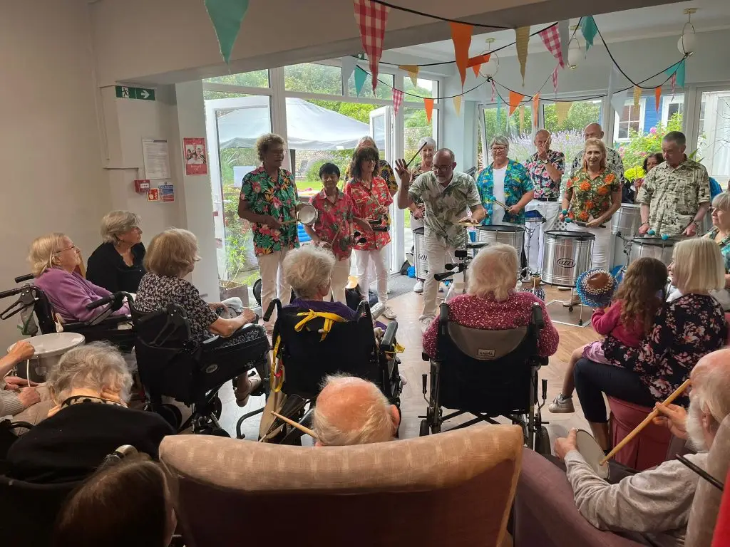 Musicians playing on percussive instruments before an elderly audience